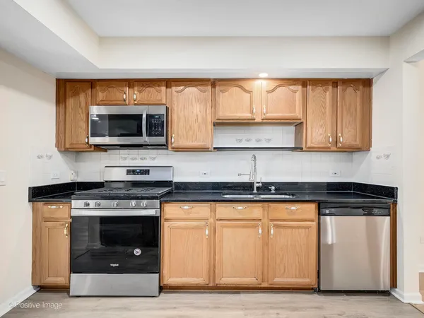 a kitchen with granite countertop a stove top oven microwave and cabinets