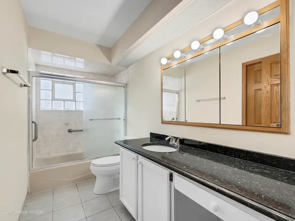 a bathroom with a granite countertop sink a toilet a mirror and shower