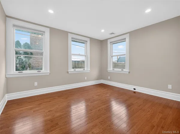 a view of an empty room with wooden floor and windows