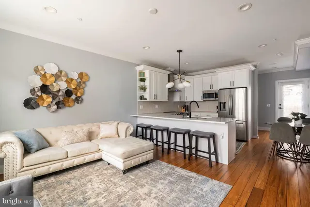 a living room with stainless steel appliances kitchen island a table and a couch