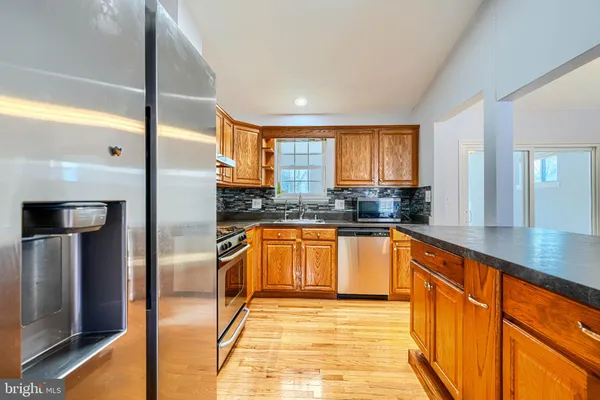 a large kitchen with stainless steel appliances granite countertop a refrigerator and a sink