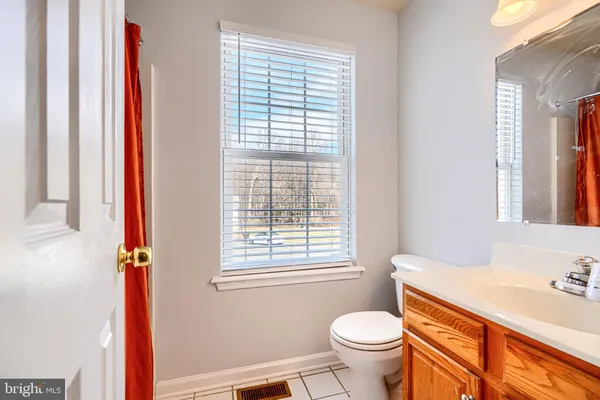 a bathroom with a granite countertop toilet a sink a mirror and a window