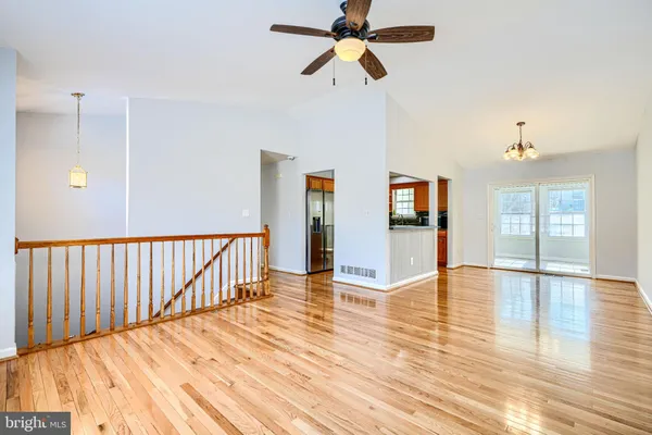 a view of an empty room with wooden floor and a ceiling fan