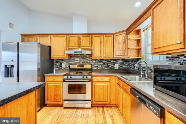 a kitchen with stainless steel appliances granite countertop a stove a sink and a microwave
