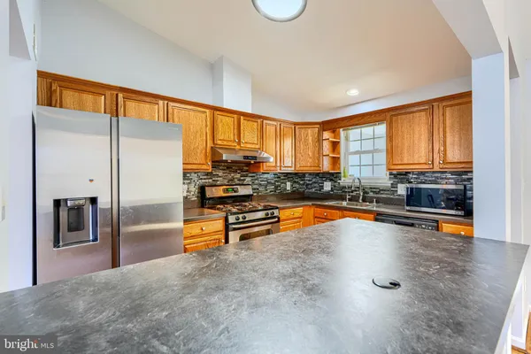 a large kitchen with stainless steel appliances a large window and a counter top space