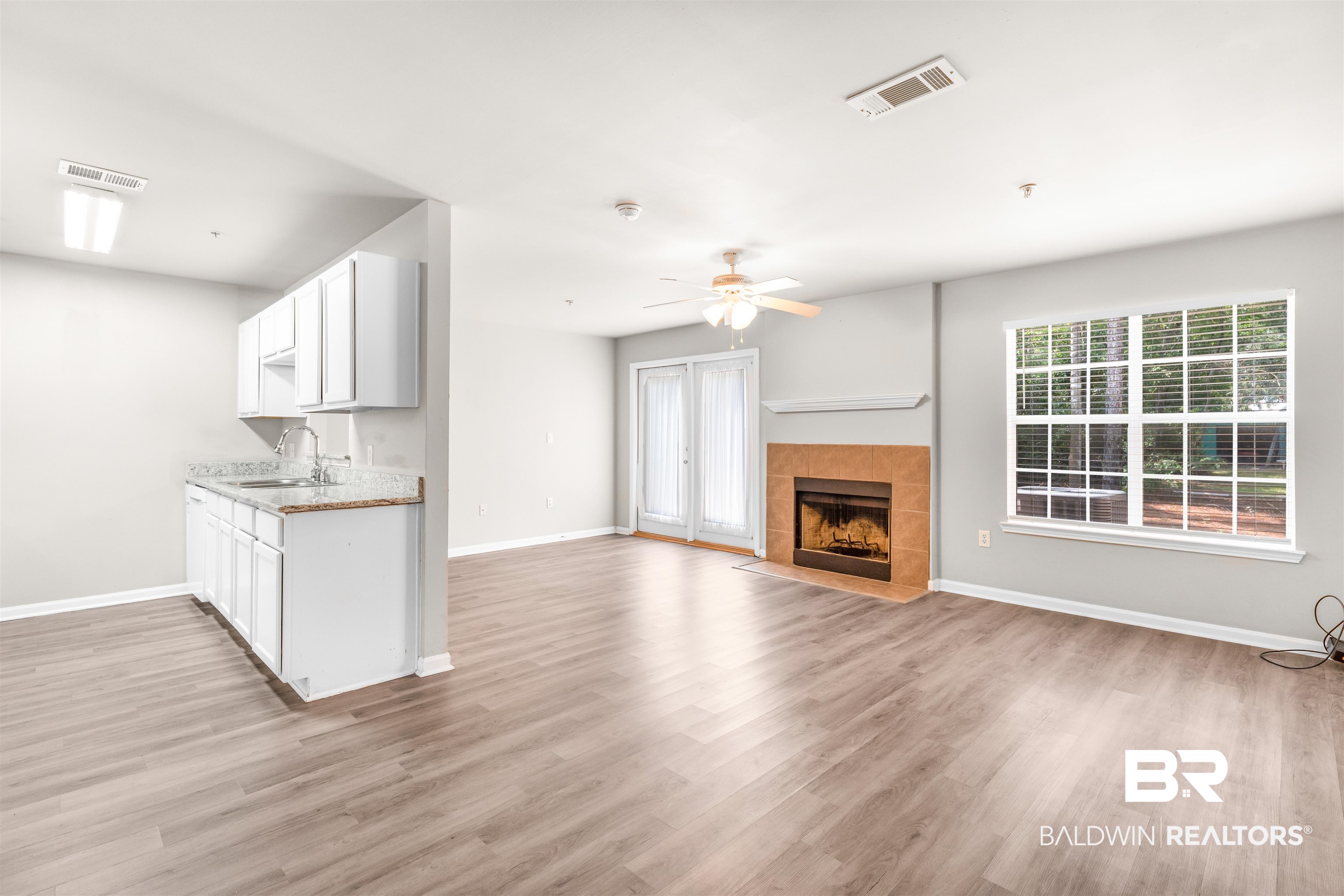 1517 Regency Road, Unit 85 Gulf Shores, AL 36542 - Photo 3 of 32 Unfurnished living room with sink, light hardwood / wood-style flooring, ceiling fan, and a tile fireplace