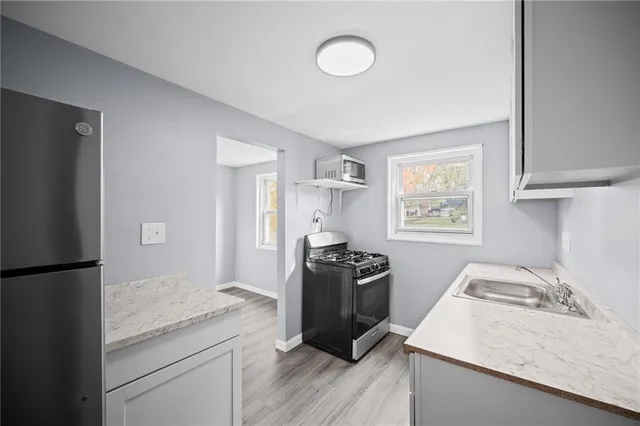 a kitchen with stainless steel appliances granite countertop a refrigerator stove sink and wooden floor