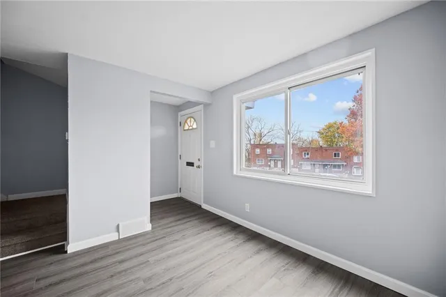 an empty room with wooden floor and window