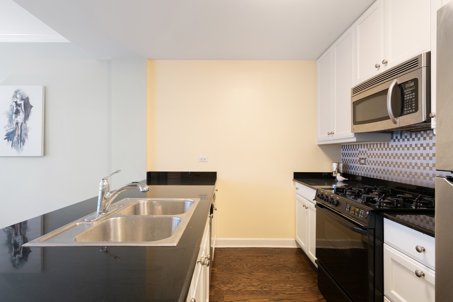 400 North Clinton Street, Unit 507 Chicago, IL 60654 - Photo 11 of 31 a kitchen with granite countertop a sink and a stove top oven