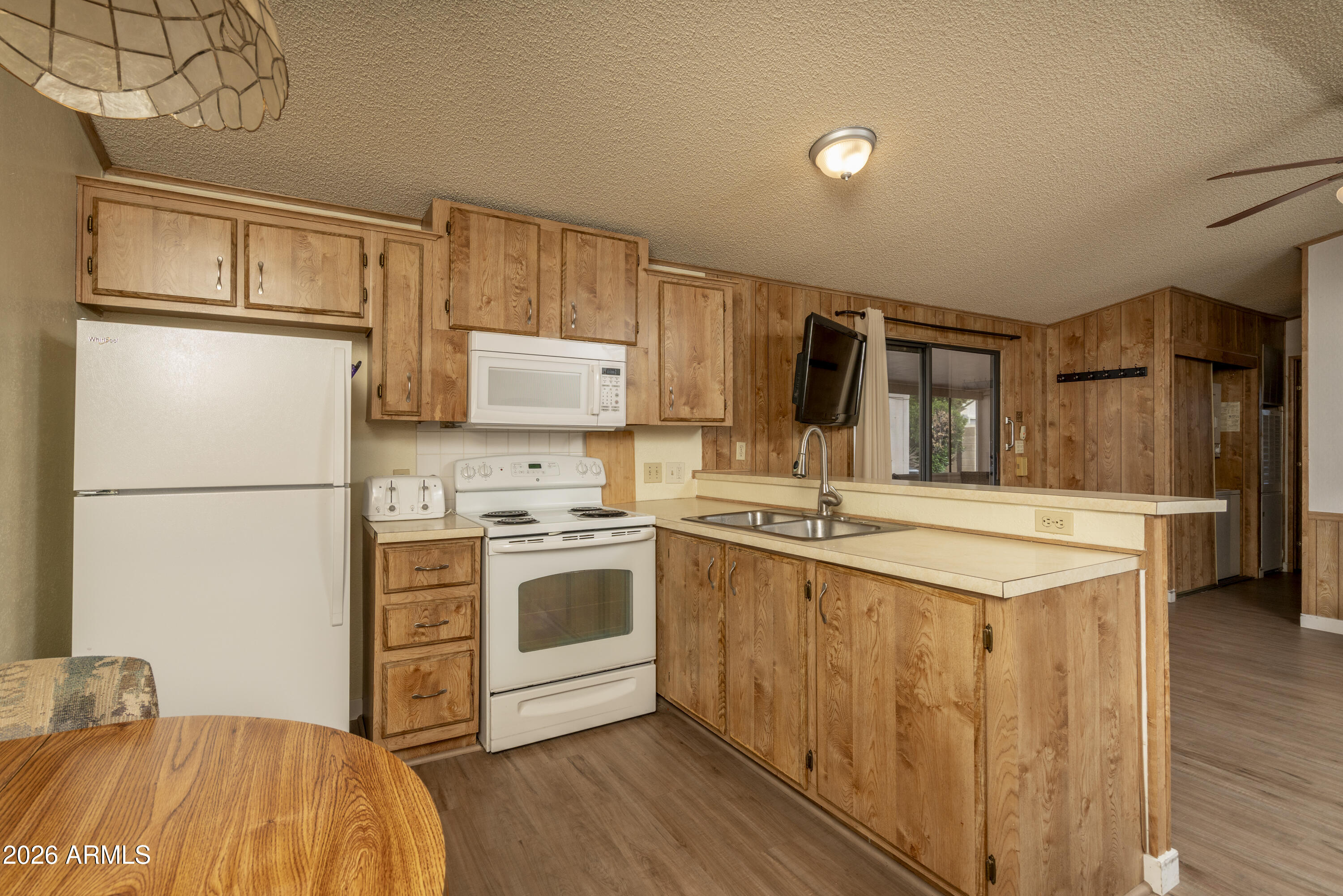 5735 East McDowell Road, Unit 466 Mesa, AZ 85215 - Photo 7 of 19 a kitchen with stainless steel appliances granite countertop a refrigerator a stove and a sink with wooden floors