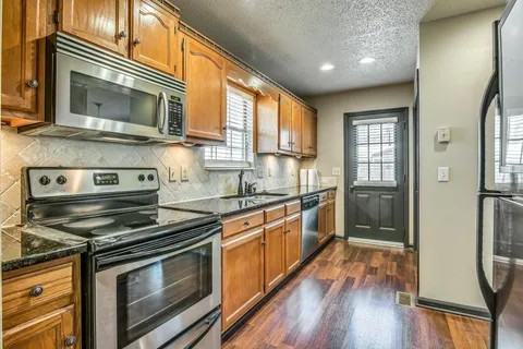 a kitchen with stainless steel appliances a stove microwave and wooden floor