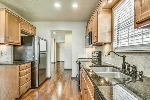 a kitchen with granite countertop a sink stove and refrigerator