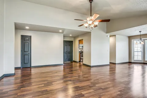 a view of an empty room with window and wooden floor
