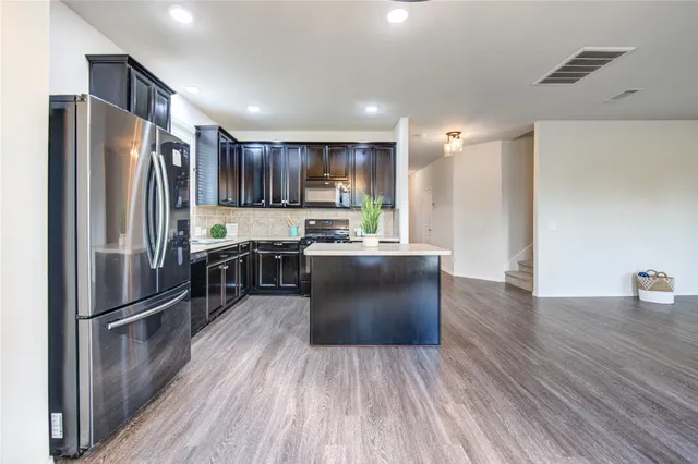 a kitchen with stainless steel appliances a refrigerator and a stove top oven