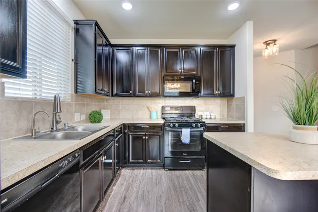 a kitchen with a sink a stove top oven and wooden floor