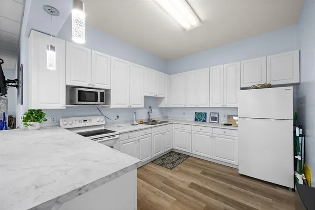 a kitchen with a refrigerator a stove a microwave and white cabinets