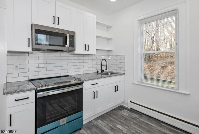 a kitchen with granite countertop a stove top oven microwave and cabinets