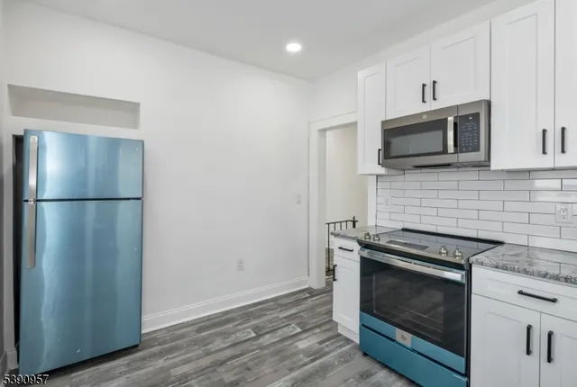 a kitchen with granite countertop cabinets stainless steel appliances and wooden floor