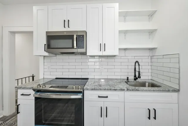 a kitchen with granite countertop a stove top oven a sink and cabinets
