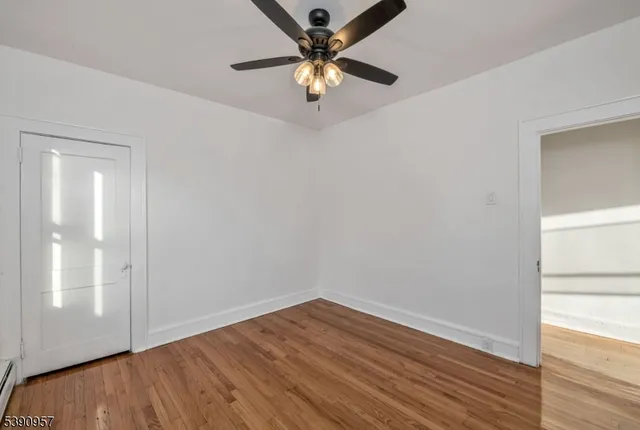 a view of an empty room with window and wooden floor