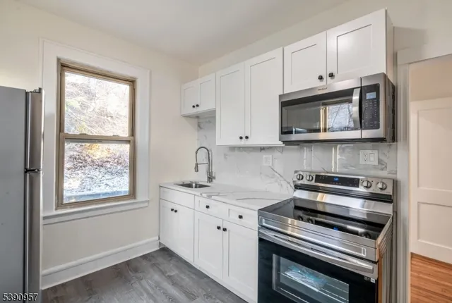 a kitchen with stainless steel appliances white cabinets and a stove top oven