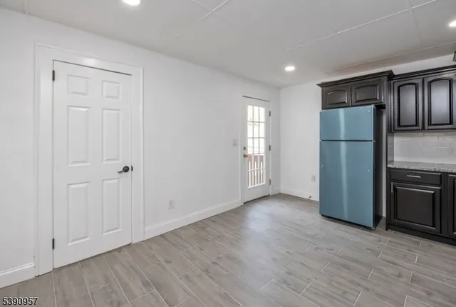 a view of a kitchen with a refrigerator a stove top oven and wooden floor