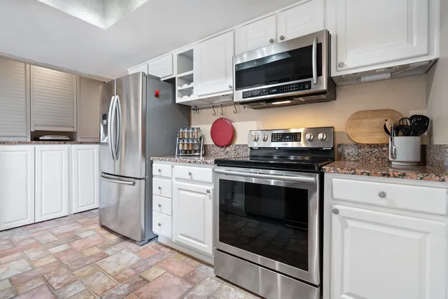 a kitchen with stainless steel appliances granite countertop a stove microwave and refrigerator