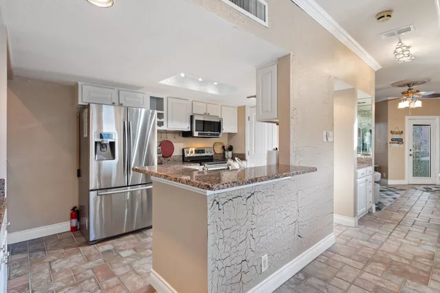 a kitchen with stainless steel appliances granite countertop a refrigerator stove and sink