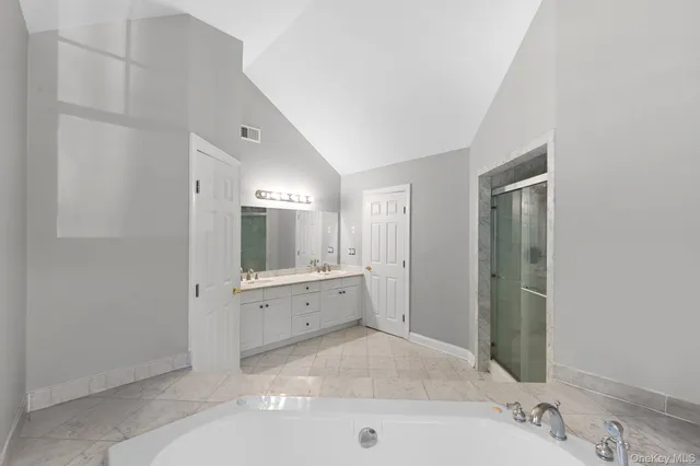 a spacious bathroom with a tub sink and mirror