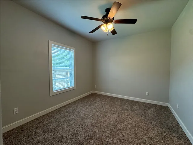an empty room with a chandelier fan and windows