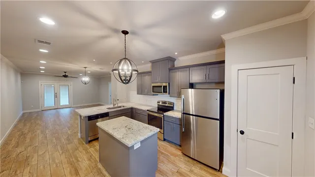 a kitchen with stainless steel appliances granite countertop a refrigerator a sink dishwasher a stove and a dining table with wooden floor