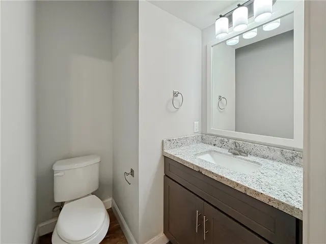 a bathroom with a granite countertop toilet and a sink