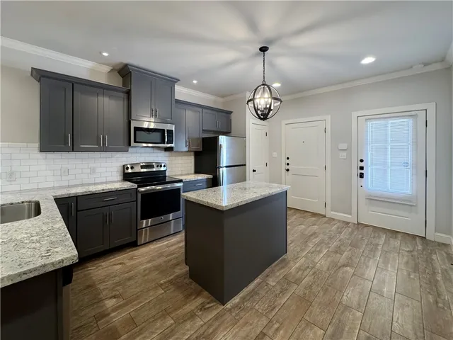 a kitchen with stainless steel appliances granite countertop a stove a sink dishwasher a refrigerator and a oven with wooden floor