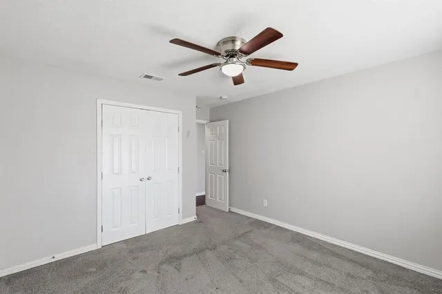 an empty room with ceiling fan and window