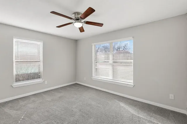 a view of an empty room with a window and a ceiling fan