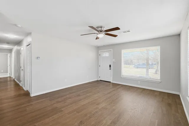 a view of empty room with wooden floor and fan