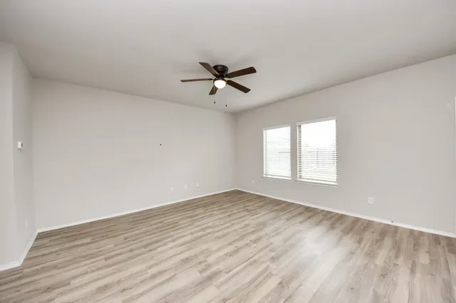 an empty room with wooden floor and ceiling fan
