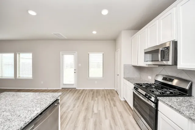a kitchen with granite countertop stainless steel appliances a stove sink and microwave