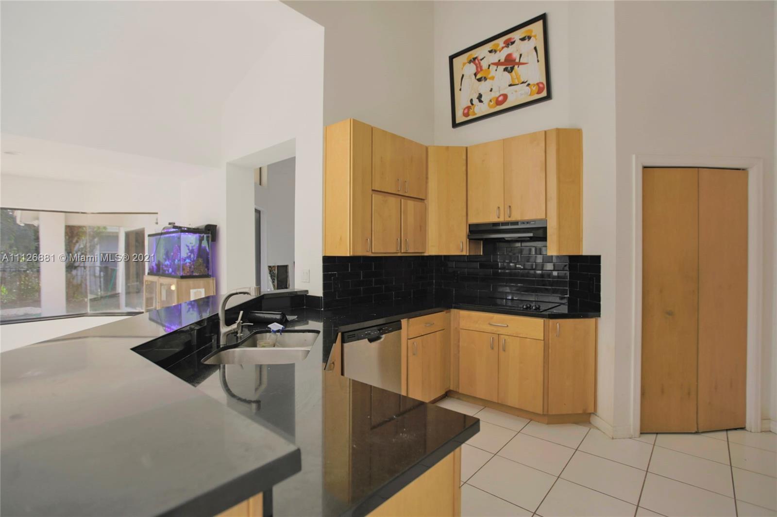 10726 Santa Rosa Drive Boca Raton, FL 33498 - Photo 13 of 26 a kitchen with granite countertop a sink a stove and a microwave