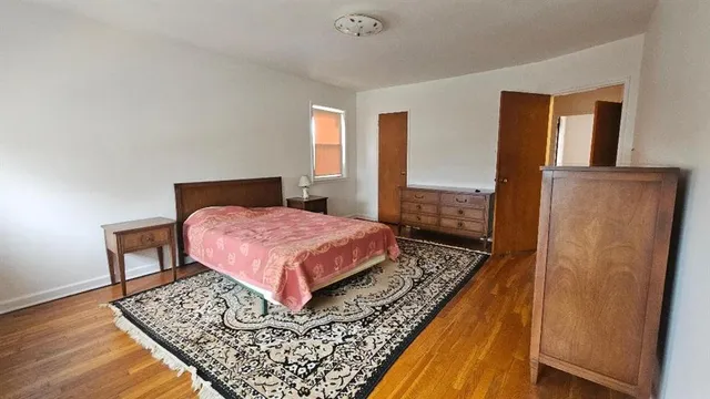 a bedroom with a bed rug and wooden floor