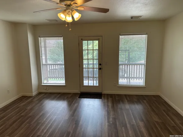 a view of an empty room with wooden floor and a window