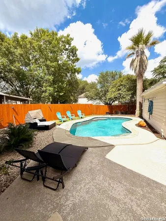 a view of a backyard with lawn chairs under an umbrella