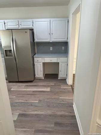 a view of a refrigerator in kitchen and an empty room