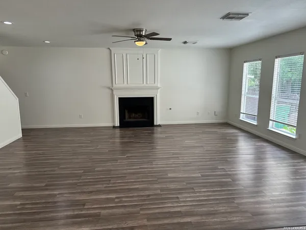 an empty room with wooden floor fireplace and windows