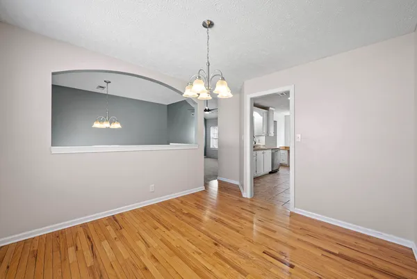 a view of a room with wooden floor chandelier and a kitchen