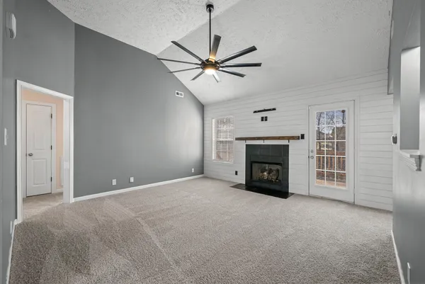 a view of an empty room with fireplace and fan