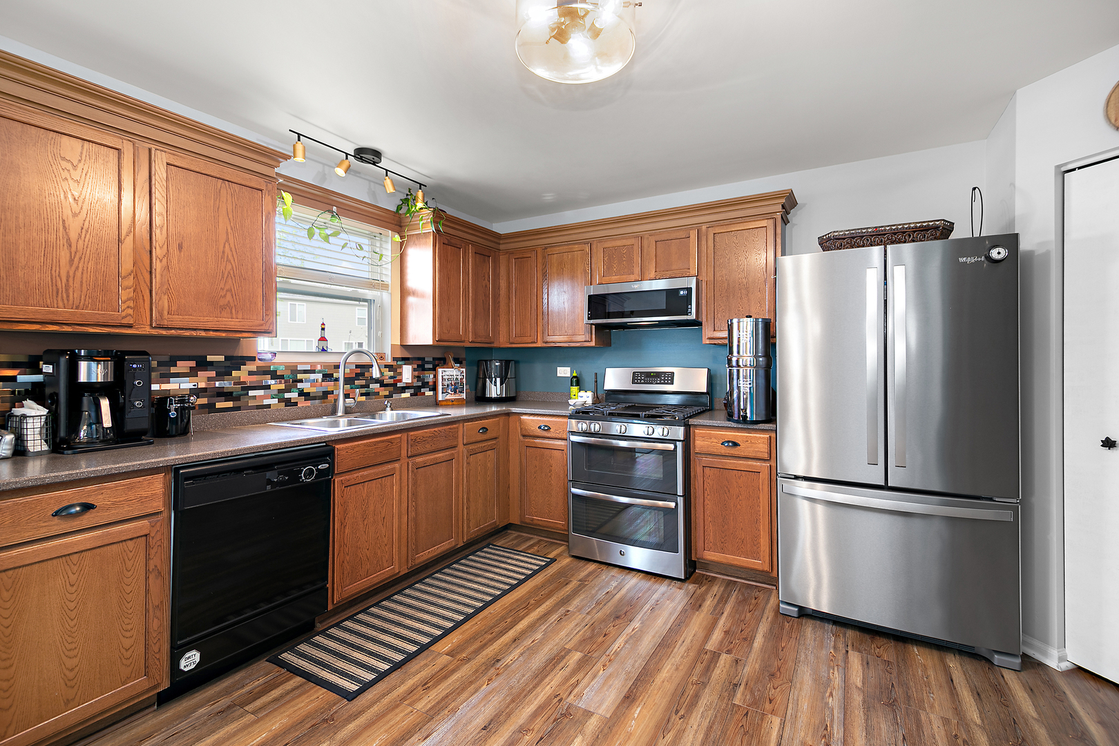 2256 Swallowtail Street Bourbonnais, IL 60914 - Photo 8 of 29 a kitchen with wooden floors stainless steel appliances and window