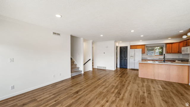 1285 Alpine Way Provo, UT 84606 - Photo 9 of 25 Wood-finish flooring throughout, recessed ceiling lighting, kitchen island with built-in sink, wood cabinetry, and stainless steel appliances