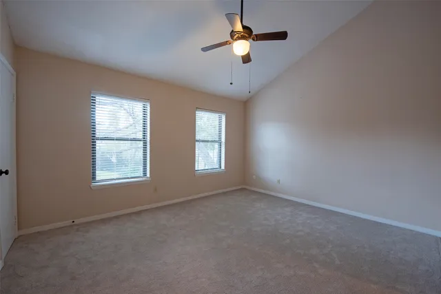 an empty room with windows and chandelier fan