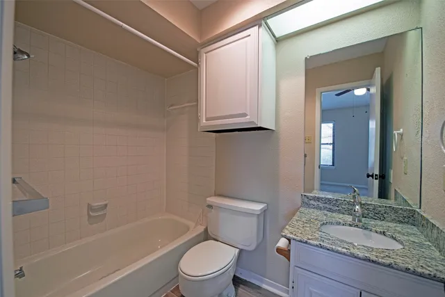 a bathroom with a granite countertop toilet a sink and a bathtub